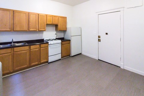 A kitchen with wooden cabinets and a white fridge.