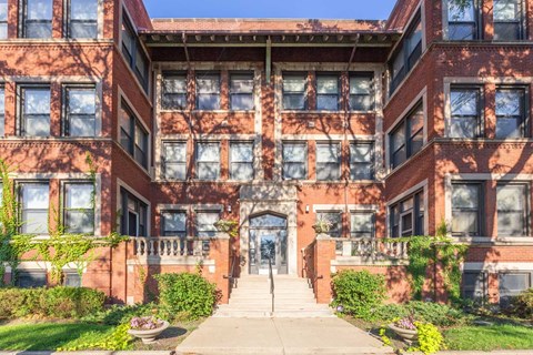 A red brick building with a central entrance and steps leading up to it.