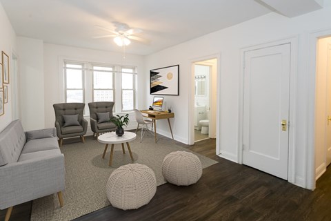 A living room with a grey sofa, two grey armchairs, a white coffee table, and a white door.