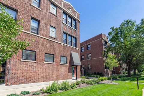 A red brick building with a green lawn in front.