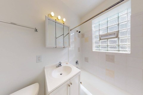 A white bathroom with a sink, mirror, and bathtub.