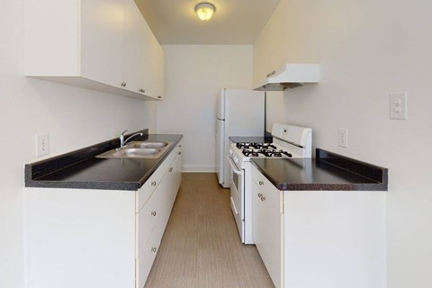 A kitchen with white cabinets and black countertops.