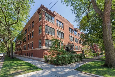 A red brick building with green trees in front.