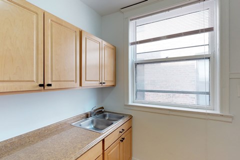 A kitchen with wooden cabinets and a window.