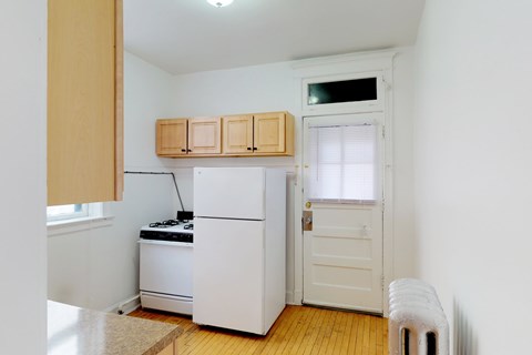 A small kitchen with a white refrigerator and a white door.