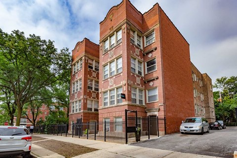 A red brick building with a black gate in front.
