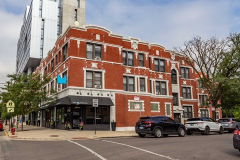 A red brick building with a black car parked in front.
