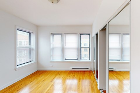 A room with wooden floors and three windows.