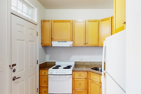 A kitchen with wooden cabinets and a white stove.