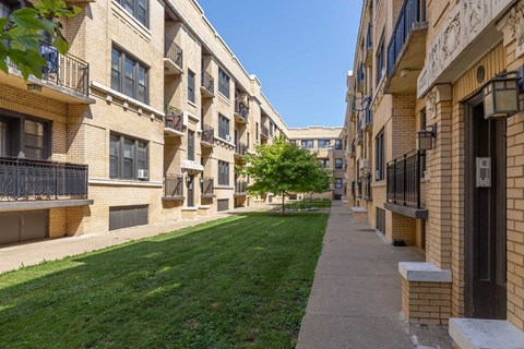 A row of apartment buildings with balconies and a green lawn in front.