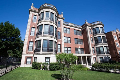 A large red brick building with a tower and a green lawn in front.