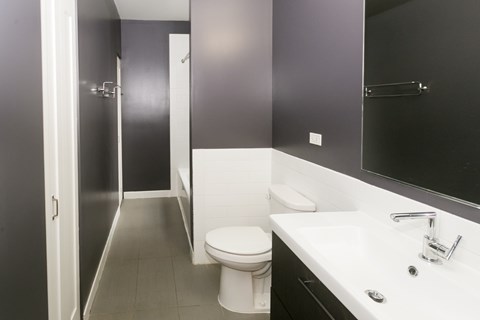 A bathroom with a toilet, sink, and mirror.