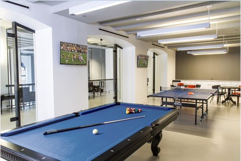 A pool table is in the middle of a room with a mirrored wall.