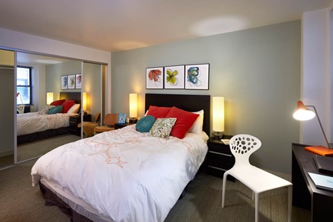 A bedroom with a large bed and a chair.