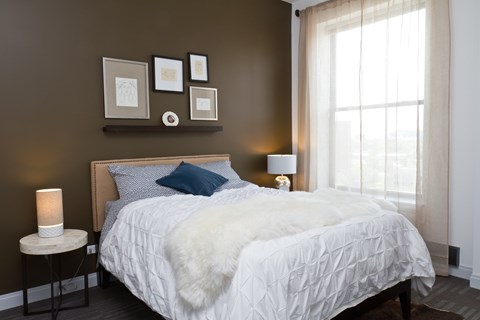A bed with a white comforter and a blue pillow is in the center of the image.