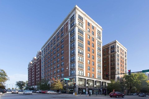 A tall building with many windows is in the middle of a street.