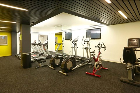 A gym with a variety of exercise equipment including treadmills, stationary bikes, and weights.