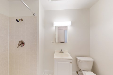 A white bathroom with a toilet, sink, and shower.