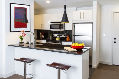 A modern kitchen with a black countertop and white cabinets.