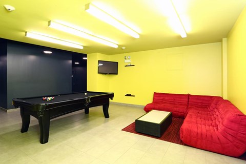 A room with a pool table and a red bean bag chair.