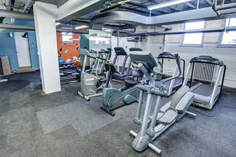 A gym with a variety of exercise equipment including treadmills, stationary bikes, and weight machines.
