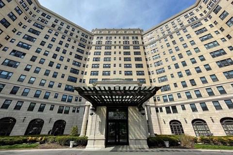 A large, beige building with a black entrance and a canopy over it.