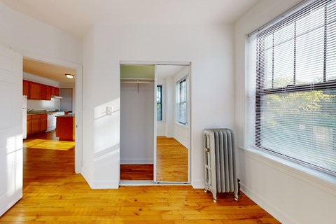 A room with a wooden floor and a window with blinds.