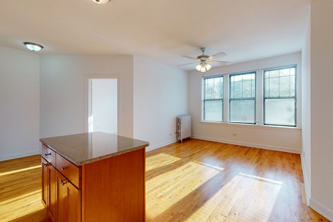 A room with a wooden floor and a table with a fan on the ceiling.