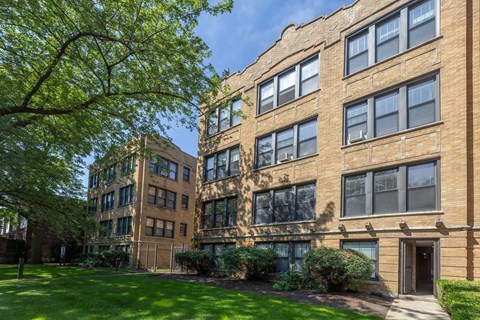 A large brown building with a tree in front of it.