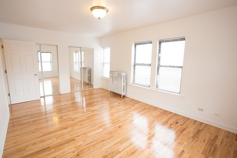 A large empty room with wooden floors and white walls.