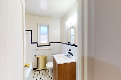 A bathroom with a toilet, sink, and window.