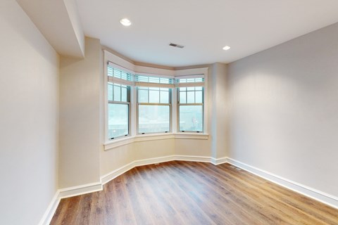 A room with a large window and wooden flooring.