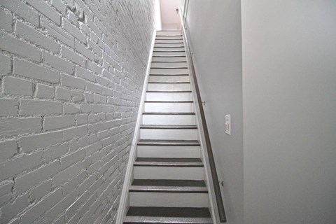 A staircase with a white brick wall on the left side.