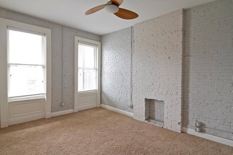 A room with a white brick wall and a ceiling fan.