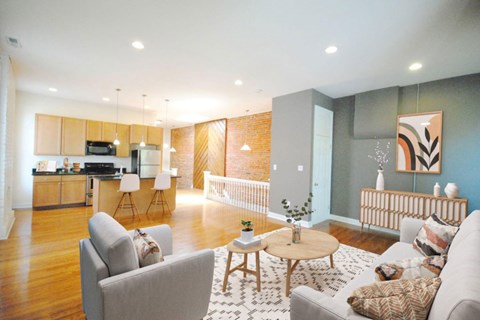 A modern living room with a grey sofa, a wooden coffee table, and a kitchen area in the background.