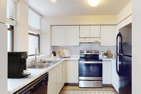 A modern kitchen with white cabinets and stainless steel appliances.