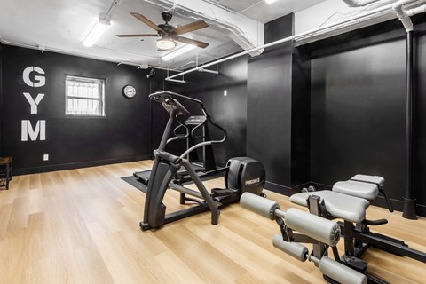 A gym with a variety of equipment including a treadmill, a stationary bike, and a rowing machine.