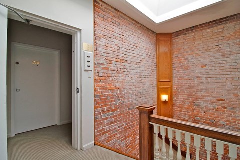 A hallway with a brick wall and a white door.