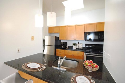 A kitchen with a black granite countertop and wooden cabinets.