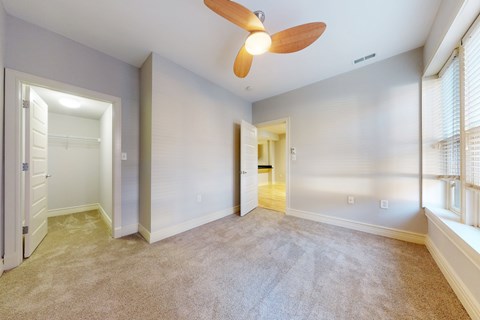 A room with a ceiling fan and carpeted floor.