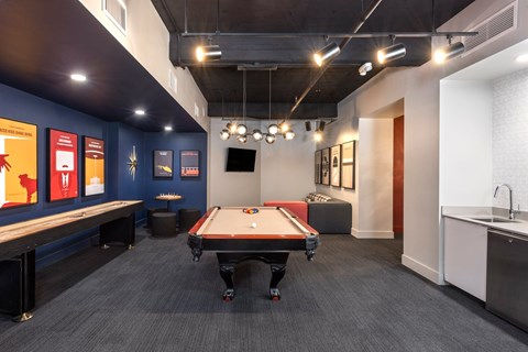 A pool table is in the middle of a room with a blue wall and a TV.