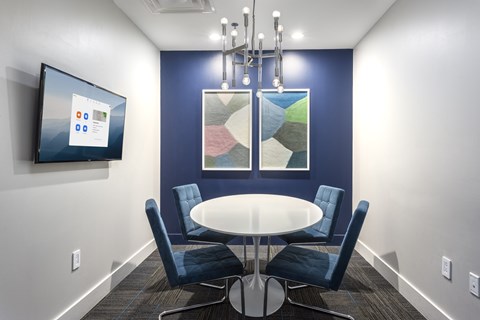 A conference room with a table, chairs, and a screen on the wall.