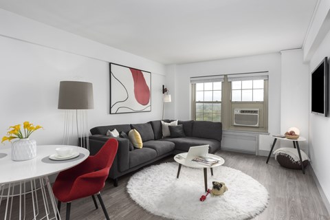 A modern living room with a grey sofa, a red chair, a white coffee table, and a large abstract painting on the wall.