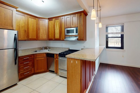 A kitchen with wooden cabinets and a stainless steel refrigerator.