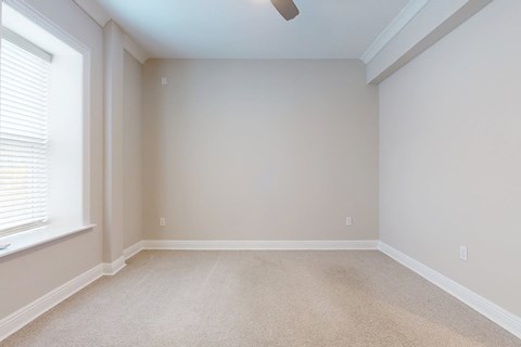 A room with a carpeted floor and a window with blinds.