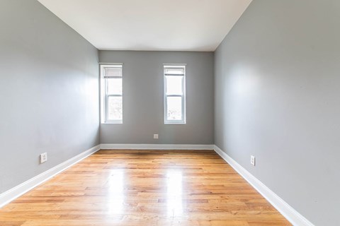 A room with wooden floors and two windows.