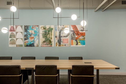 A conference room with a long table and chairs and a wall of posters.