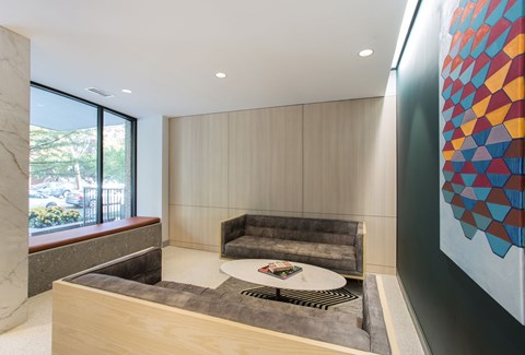 A modern living room with a grey couch and a large abstract painting on the wall.