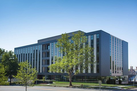 A modern building with a glass facade and a tree in front.