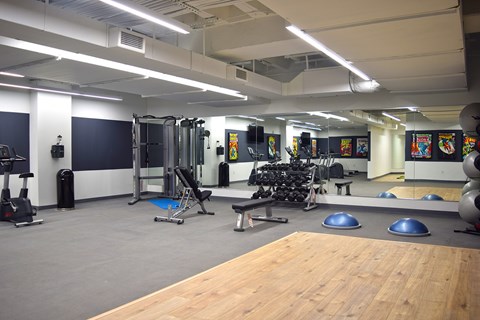 A gym with a variety of equipment including weights, a bench, and a mirror.